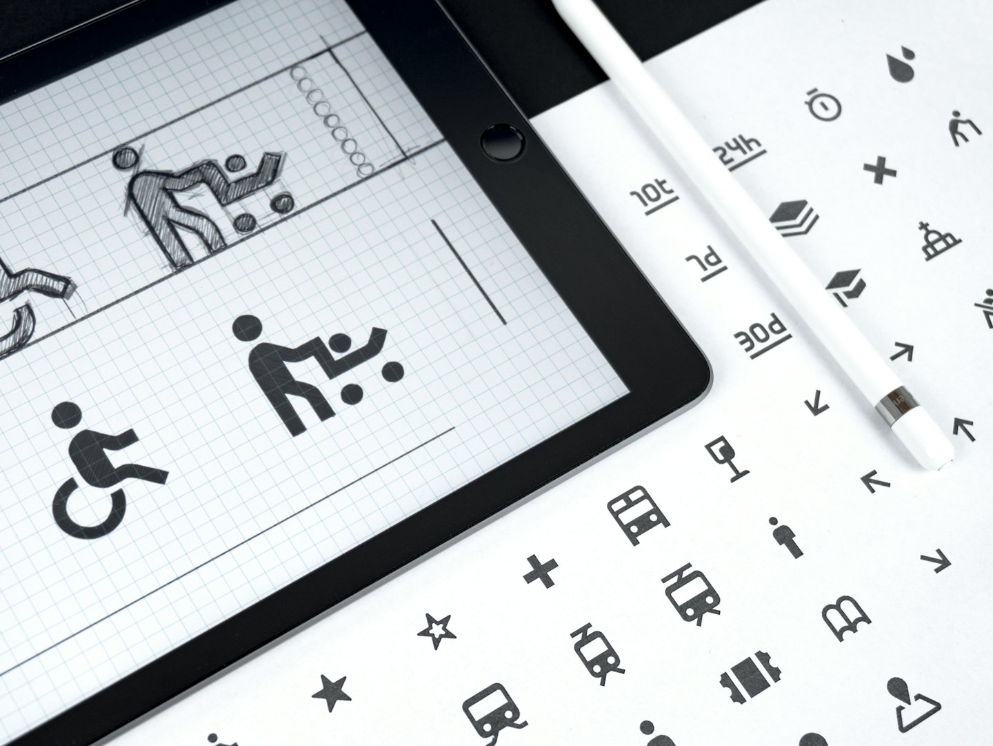 Tablet zeigt Grafikdesign-Konzepte neben Stift und Symbolblatt.