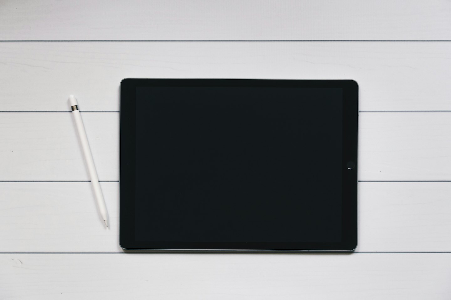 Schwarzes Tablet und weißer Stift auf Holzbrett.